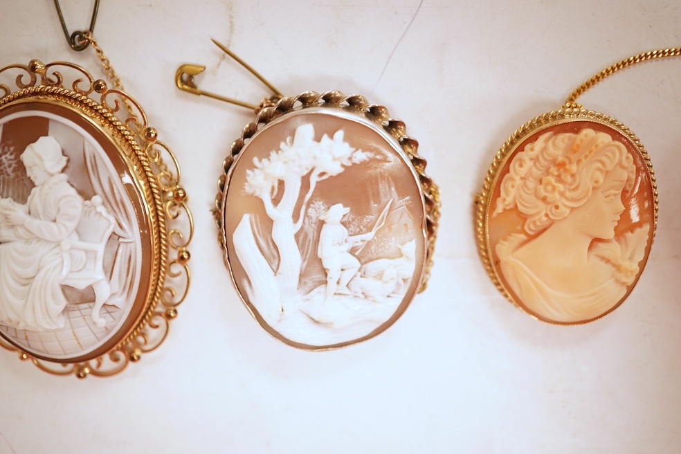 A collection of five cameo brooches, each of oval outline, set with a carved shell cameo, variously depicting three women in profile, a seated lady doing needlework, and a pastoral scene of a shepherd, longest 6.8cm, thr